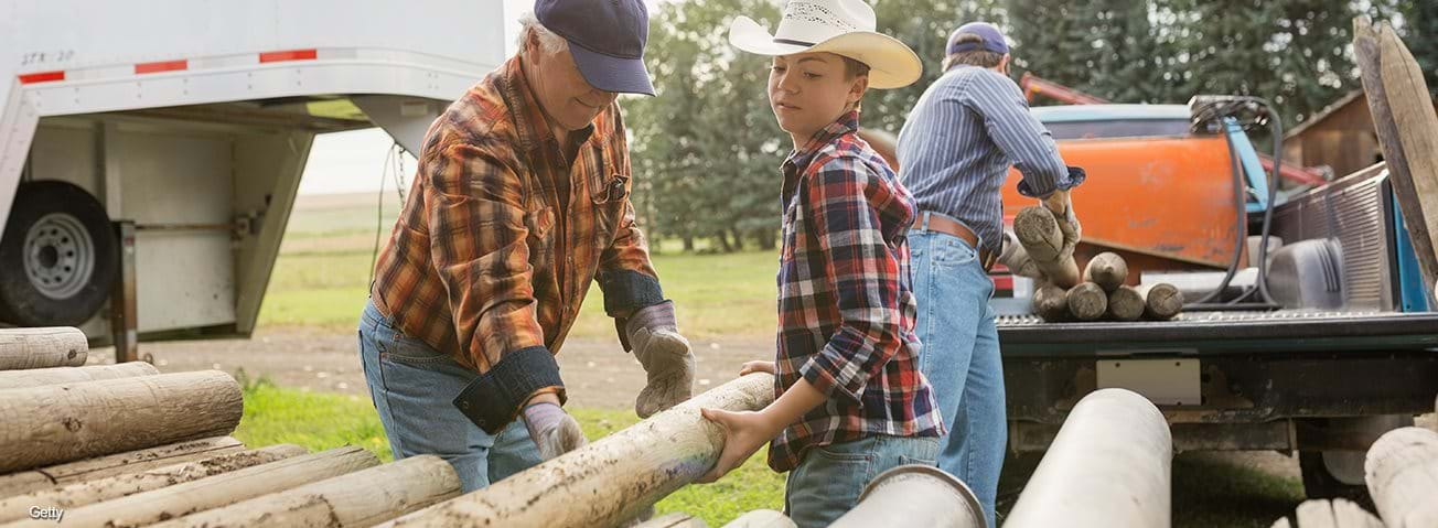 Multi-generation farmers unloading logs on farm