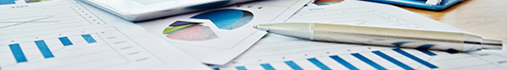 Close-up of chart documents, computer tablet and pen on desk