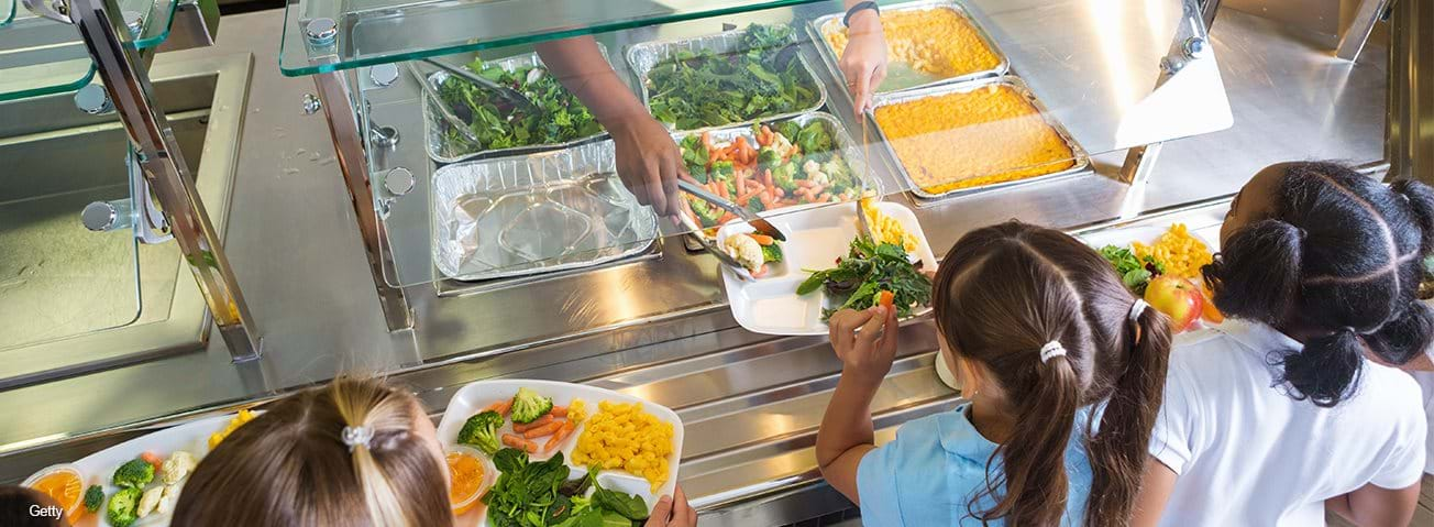 Two girls being served school lunch