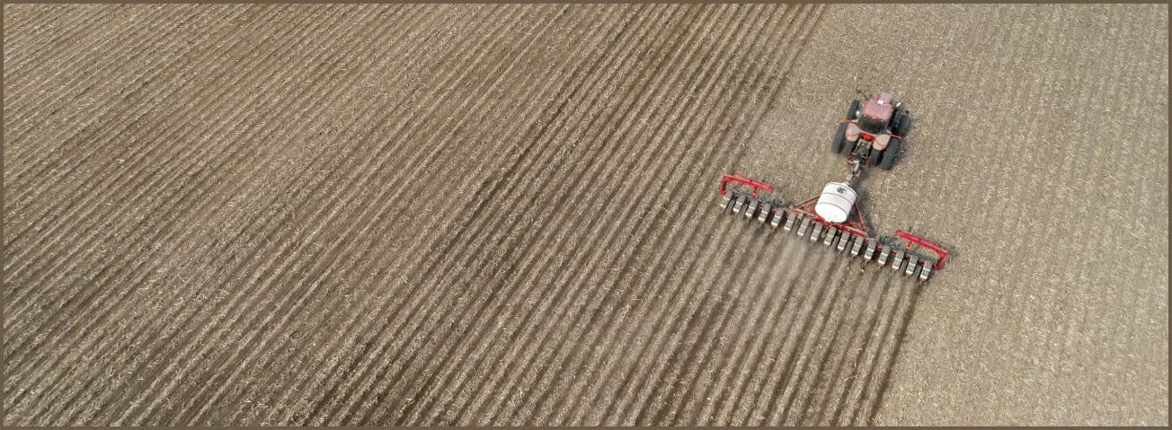 Photo of a crop field being sown with a planting machine.