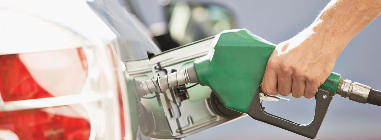 Photo of a hand holding a gas pump and filling a car with gas.